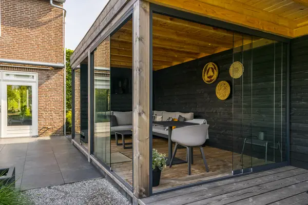 Glasschiebewände unter einer überdachten Terrasse mit Sitzecke