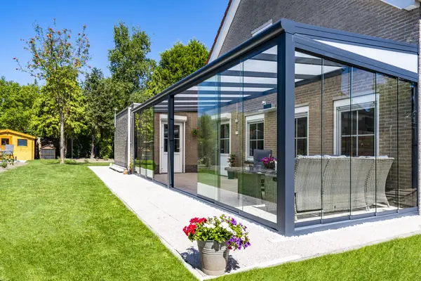 Terrassenüberdachung aus Aluminium mit Glasschiebewänden an einem Wohnhaus